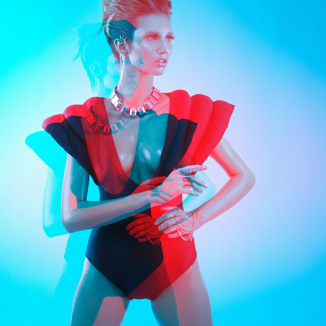 Graphic representation of model Adeline Petit adorned with magnificent jewels and a very original bodysuit, captured in an artistic electric blue and red image by photographer Etienne Delorme for Faust Magazine.