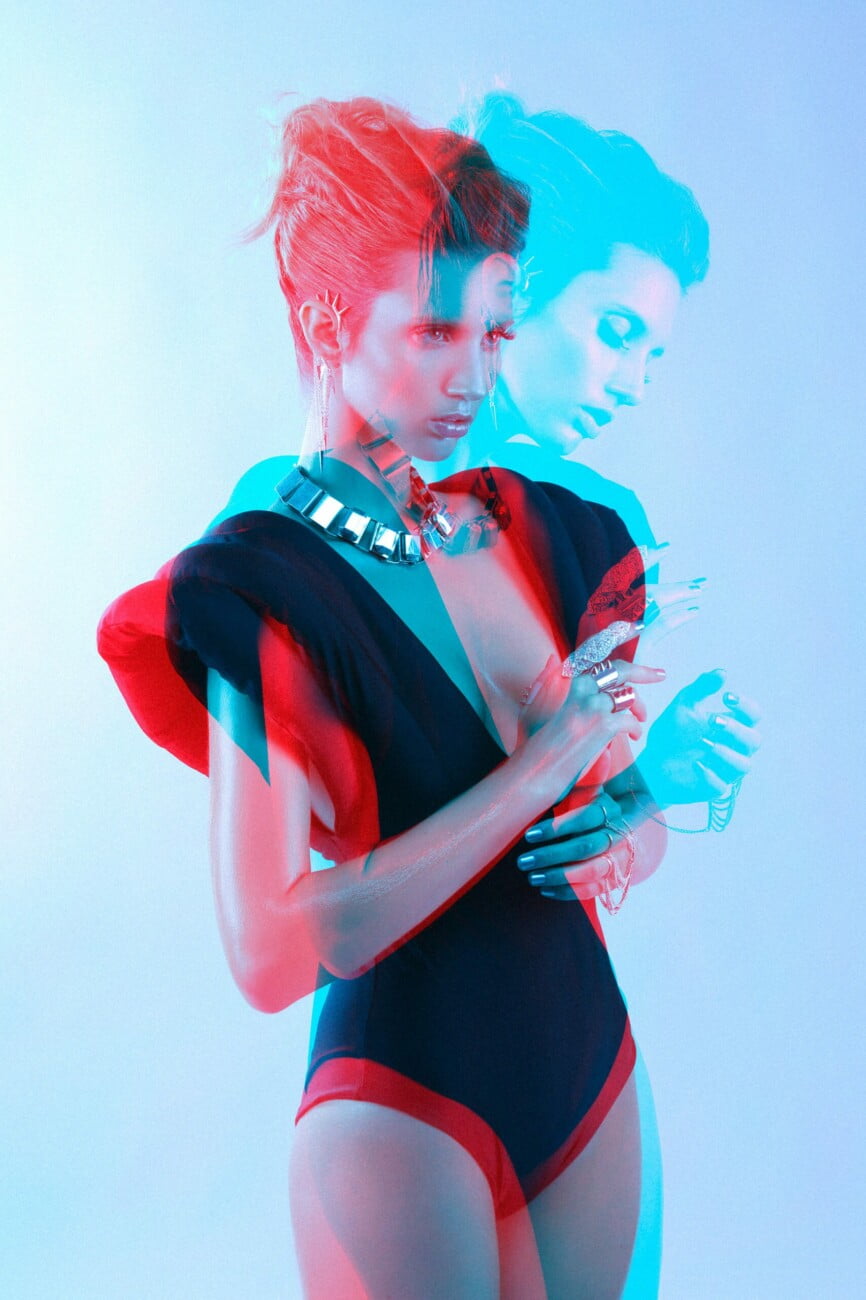 Dynamic capture of model Adeline Petit in elegant attire and stunning jewelry, presented in an electric blue and red artistic image by photographer Etienne Delorme for Faust Magazine.